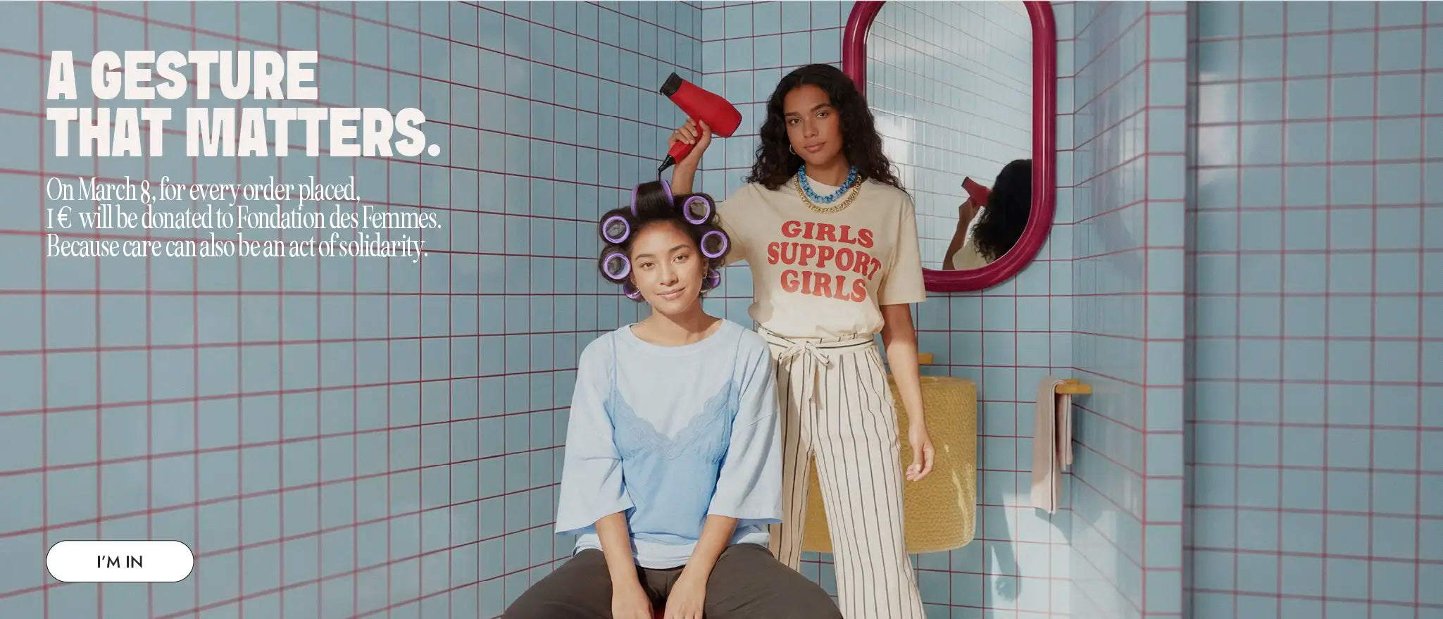 Two women in a colorful hair salon scene with curlers and a hair dryer representing the Myriam K Paris International Women’s Day beauty campaign.