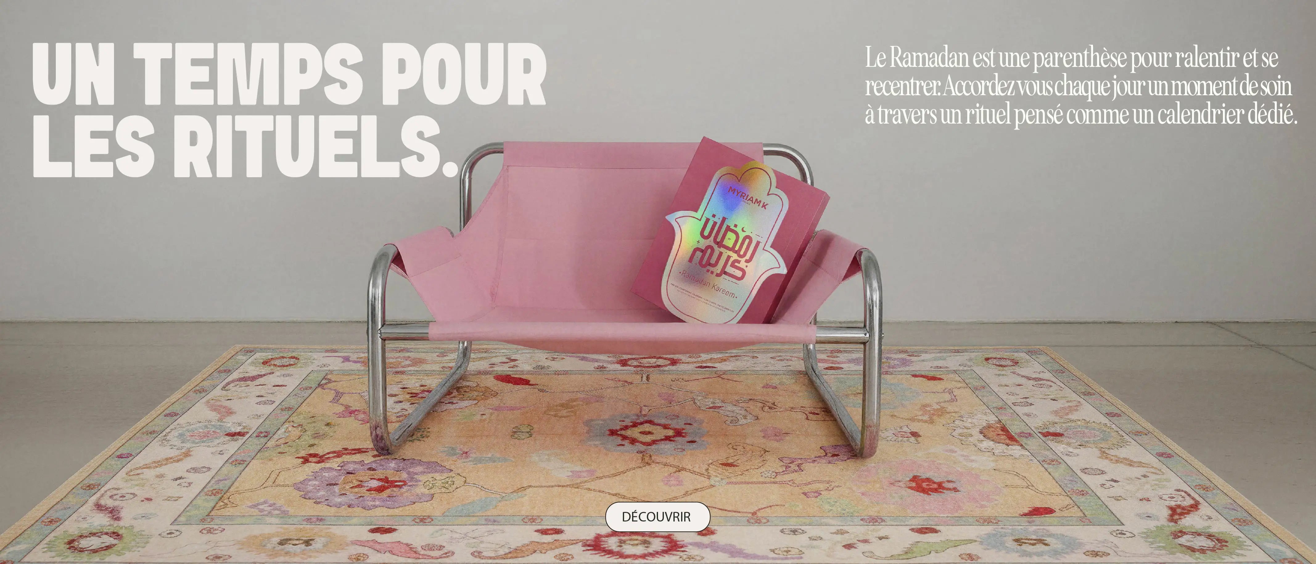 Banc rose avec un calendrier de rituels Ramadan Myriam•K Paris, posé sur un tapis décoratif, évoquant un moment de calme, de soin et de reconnexion pendant le Ramadan.