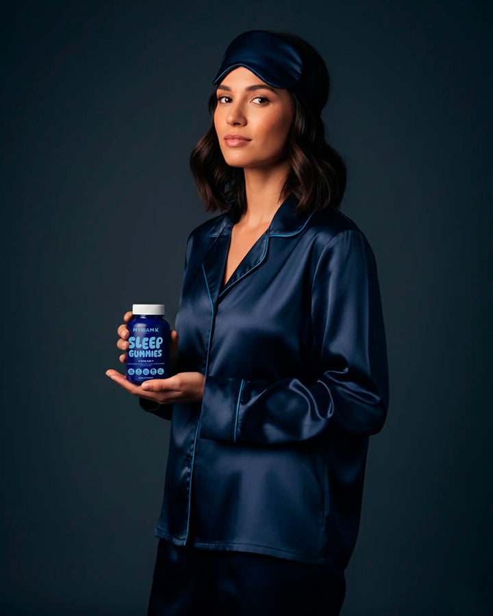 Femme en pyjama bleu tenant le flacon de Sleep Gummies Myriam•K, compléments vegan au goût fruité pour améliorer le sommeil et la détente