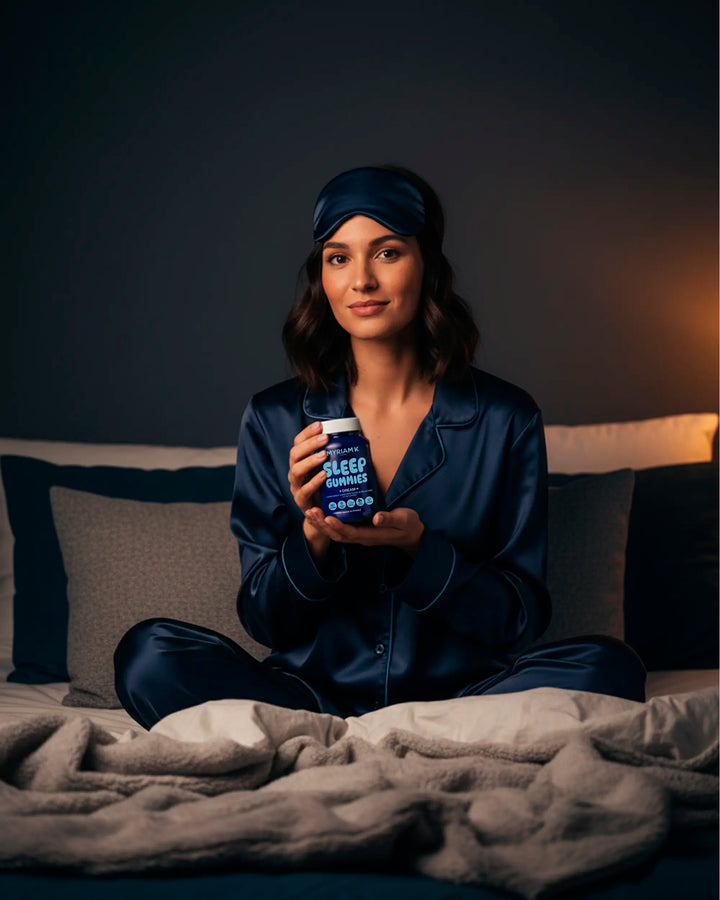 Femme en pyjama assise sur son lit avec Sleep Gummies Myriam•K, gommes à la mélatonine et plantes pour un sommeil réparateur et naturel